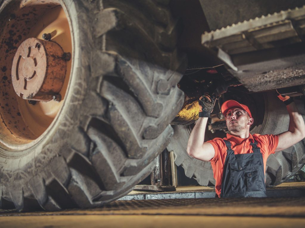 Mechanic performing heavy vehicle repair under a truck